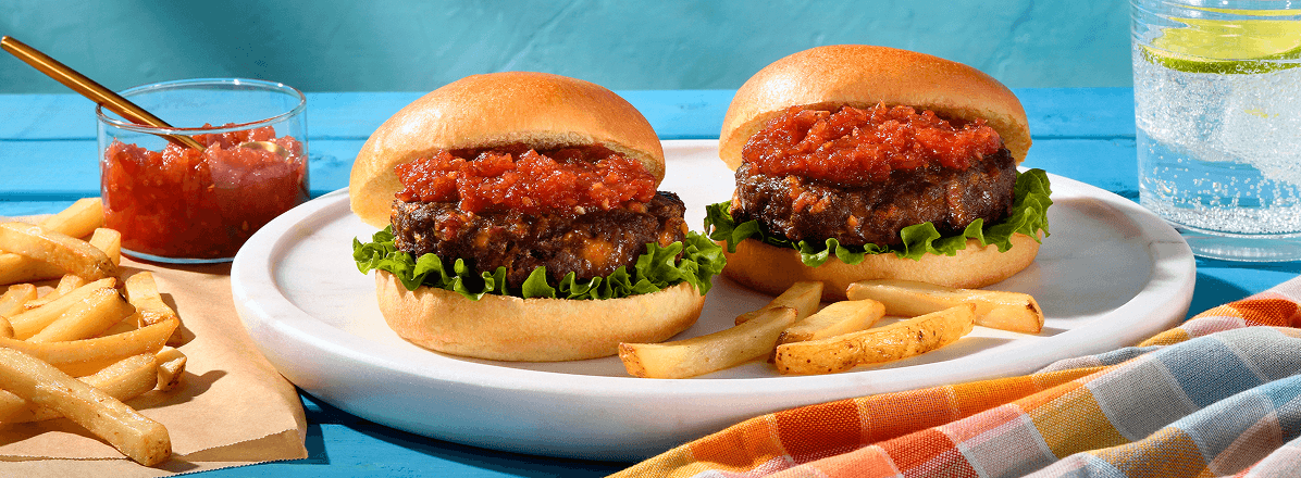 Cheddar & Bacon medium chuck burgers topped with tomato relish with fries off to the side
