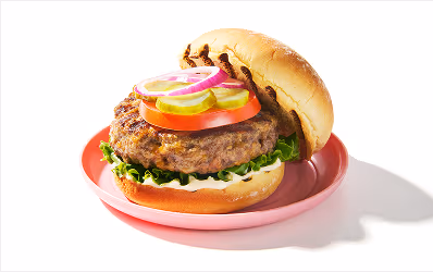 Open-face burger, dressed with mayo, lettuce, tomato, pickle and red onion.