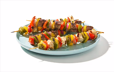 Variety of grilled kebabs, including chicken, beef and pork skewered with bell peppers and red onion.