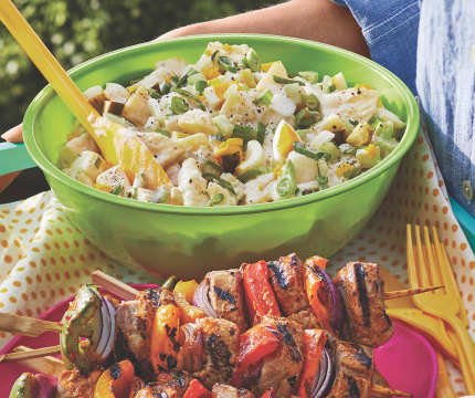 serving tray with green bowl of dill pickle potato salad and a plate of grilled kabobs