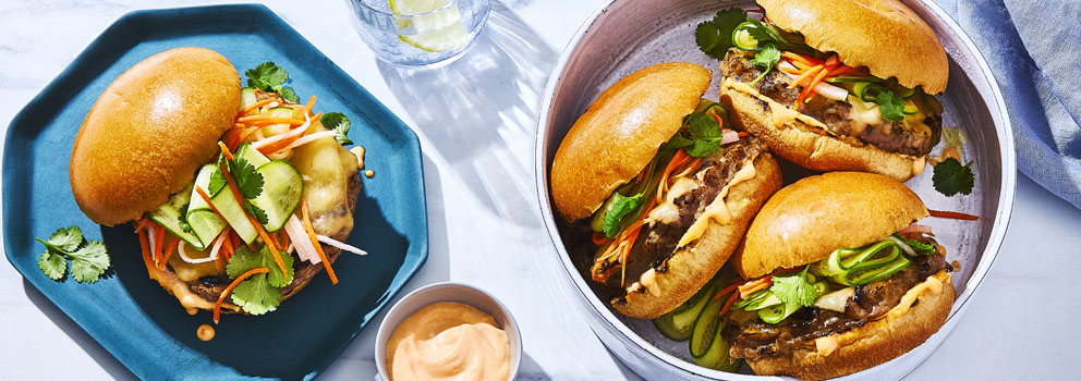 serving plate of three Bánh Mì-Style Burgers, and a side plate with a burger and side of creamy sauce