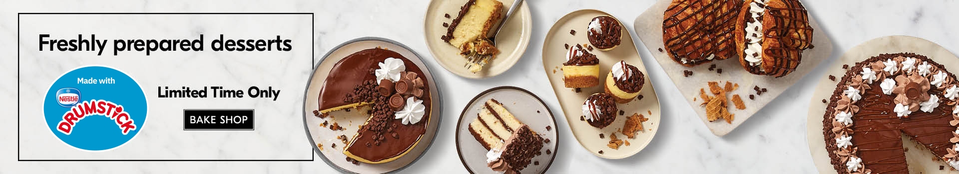 Selection of NESTLÃƒâ€° DRUMSTICK infused desserts ranging from a cake, cake slices and croissants on white plates, sitting on a neutral, marbled background.