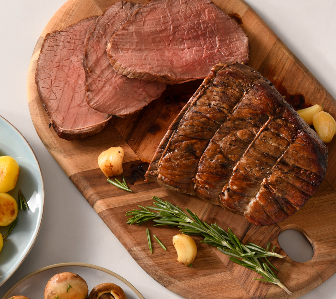 Inside round oven roast on cutting board with side of potatoes