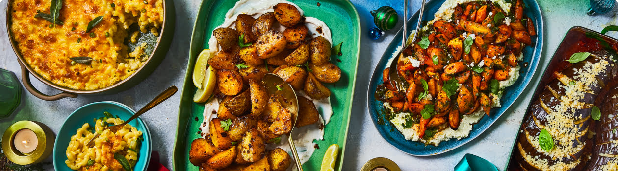 Overhead shot of side dishes like hasselback eggplant, mac and cheese, and piri piri potatoes