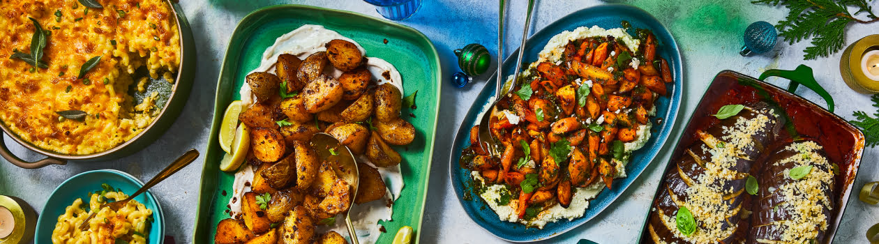 Overhead shot of side dishes like hasselback eggplant, mac and cheese, and piri piri potatoes