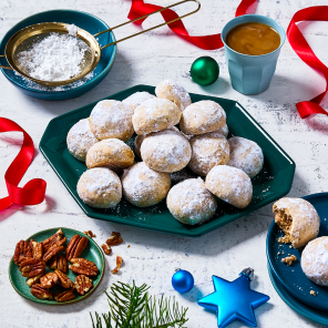 A stack of snowball cookies on a plate and a small plate with a full cookie and one that has a bite out of it