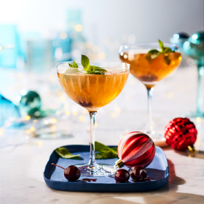 Canadian Tuxedo in two coupe glasses on a marble surface with scattered holiday decorations.