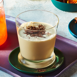 Coffee flip in a cocktail glass on a purple serving tray