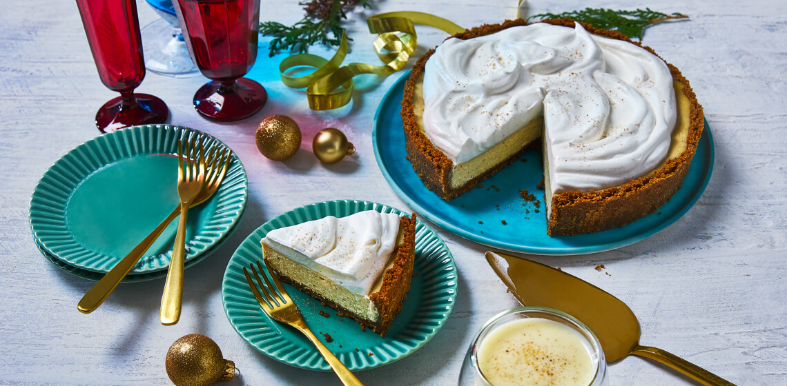  Eggnog cheesecake on blue plate with slice cut out and placed on a plate