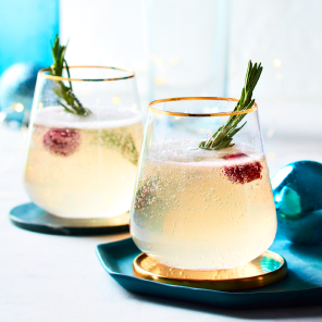 French 57 in gold-rimmed glasses, with a cherry and rosemary garnish in the glass