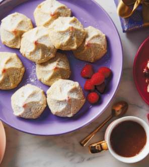 Holiday cookies plated with coffee cups and red napkins.