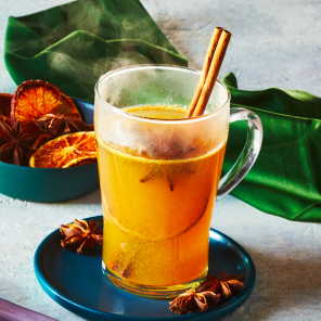 Hot buttered cider in a tall glass mug on a blue plate