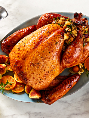 Roast turkey with oranges and stuffing on white marble table.