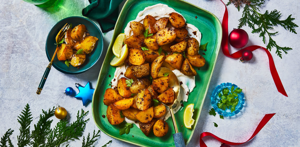 Piri Piri potatoes on a green serving platter with bowl of one serving on the side