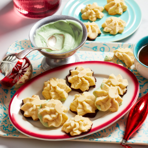 A plate of whipped shortbread cookies and a cup of tea on a blue and white tray