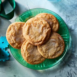 Cinnamon sugar topped snickerdoodle cookies on a blue plate next to a glass of milk