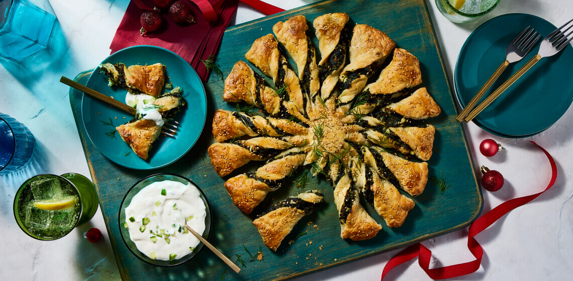 Overhead shot of spanakopita twists with one twist on plate to the side with dip