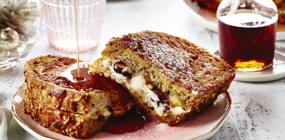 Shot of stuffed eggnog french toast on a pink plate with maple syrup drizzle