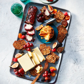 Cheese wedges, crackers, and fruit on a blue platter.