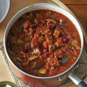 Overhead shot of a bowl of beef chili with sour cream and green onions on the side.