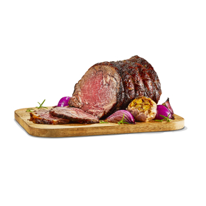 Cook prime rib roast on a wooden cutting board with roasted garlic, onions, and sprigs of rosemary