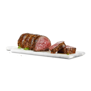 A cooked beef tenderloin road has two pieces cut off, resting on a cutting board