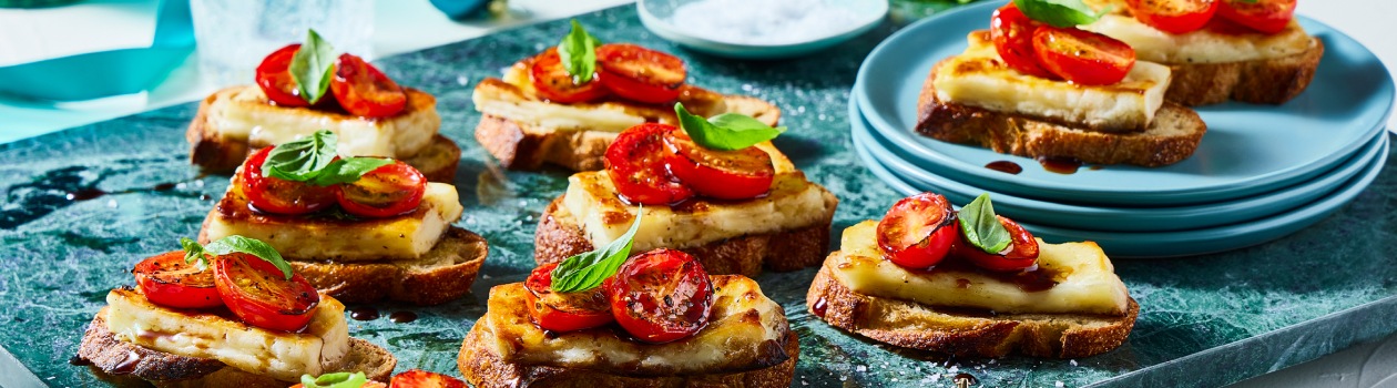 Caprese halloumi crostini on a turquoise board