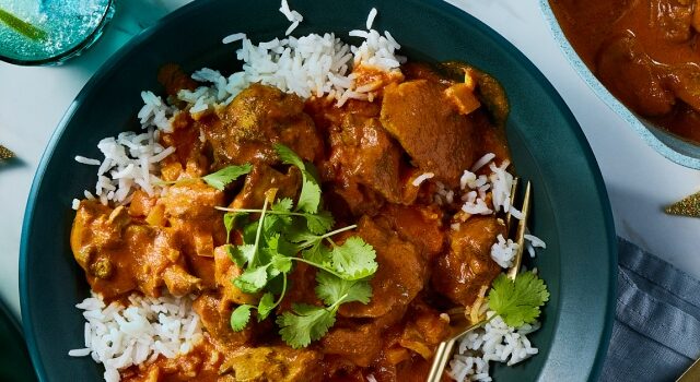 Plate of chicken tikka masala on a bed of rice with a side of naan.