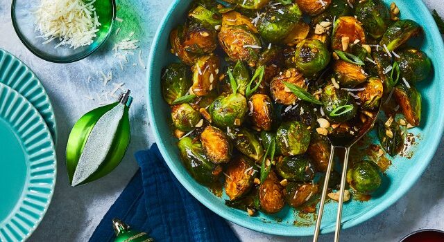 Bowl of gochujang brussel sprouts with peanuts and green onions to the side