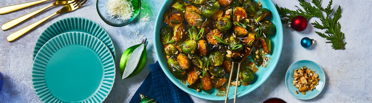 Bowl of gochujang brussel sprouts with peanuts and green onions to the side