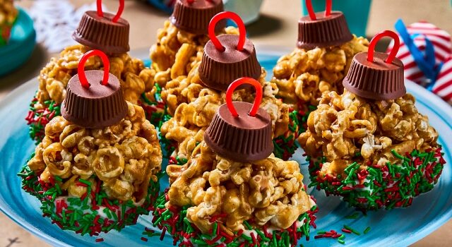 Popcorn holiday ornaments with green and red sprinkles sitting on a blue tray