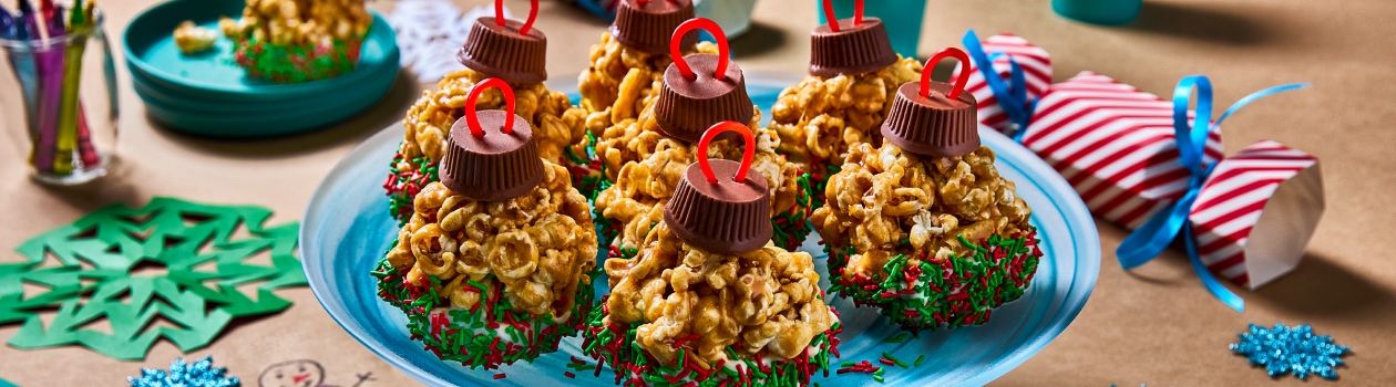 Popcorn holiday ornaments with green and red sprinkles sitting on a blue tray