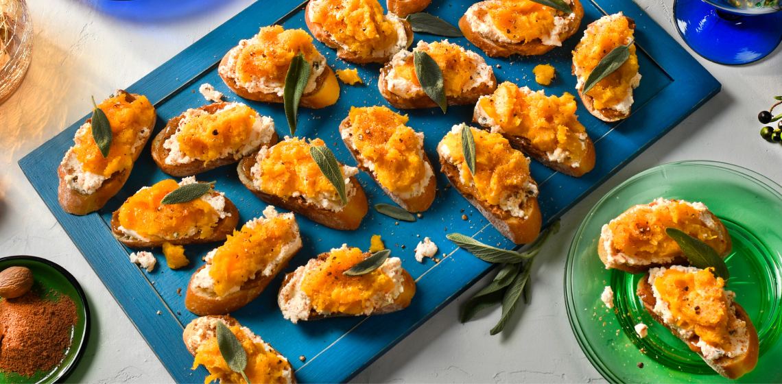 Several roasted butternut squash crostini on a blue rectangular plate