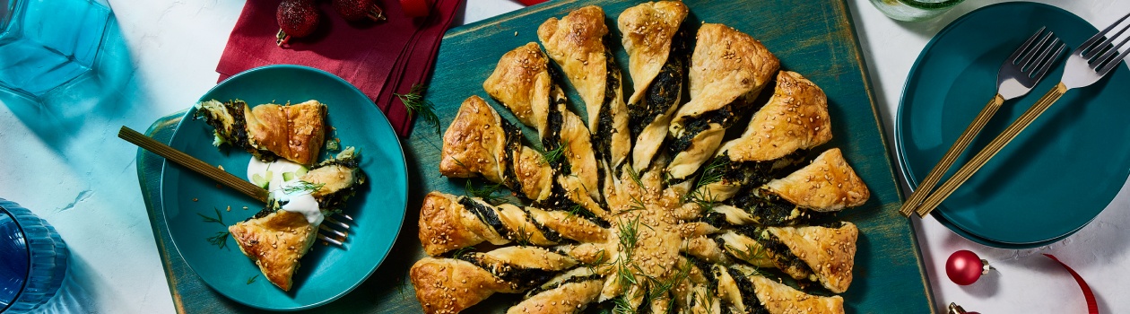 Overhead shot of spanakopita twists with one twist on plate to the side with dip