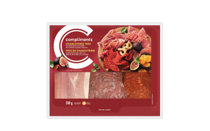 Clear plastic package of Compliments Charcuterie Trio (Dry-Cured Spicy Genoa Salami, Dry-Cured Genoa Salami & Prosciutto) with red label.