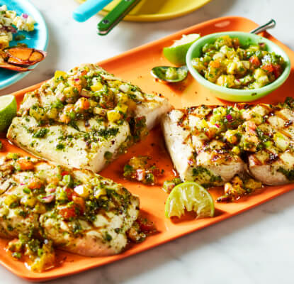 Tabletop with platters of food, including grilled mahi-mahi, lobster and tuna.