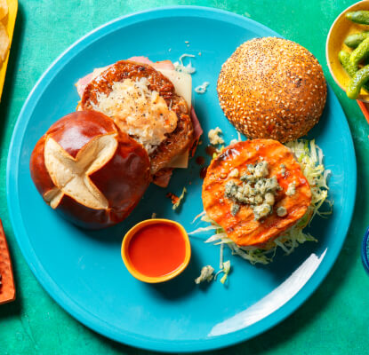 Tablescape with three plates of burgers, and a side bowl of chips