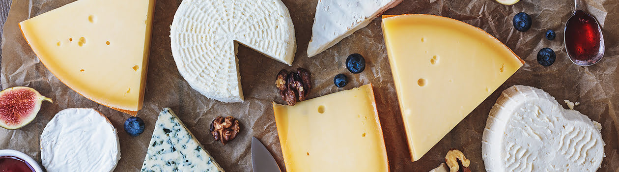 Overhead of different cheeses on a rustic tabletop.