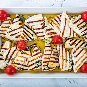 Grilled halloumi on a pan drizzled with olive oil and cut cherry tomatoes