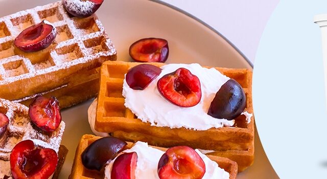 Freshly made waffles topped with pitted cherries cut in half.