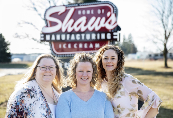 Three women standing outside and standing in front of a Shaw’s Ice Cream sign.