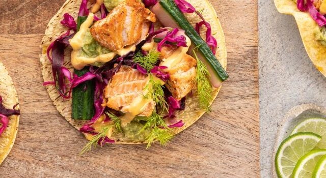 Overhead shot of crispy salmon tacos topped with fresh dill and red cabbage