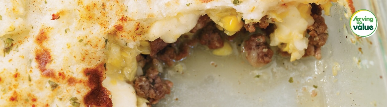 Casserole dish of shepherds pie with scoop out from corner